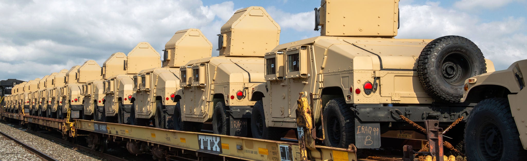 Multiple armored vehicles on an open train car showing ways to ship military equipmen