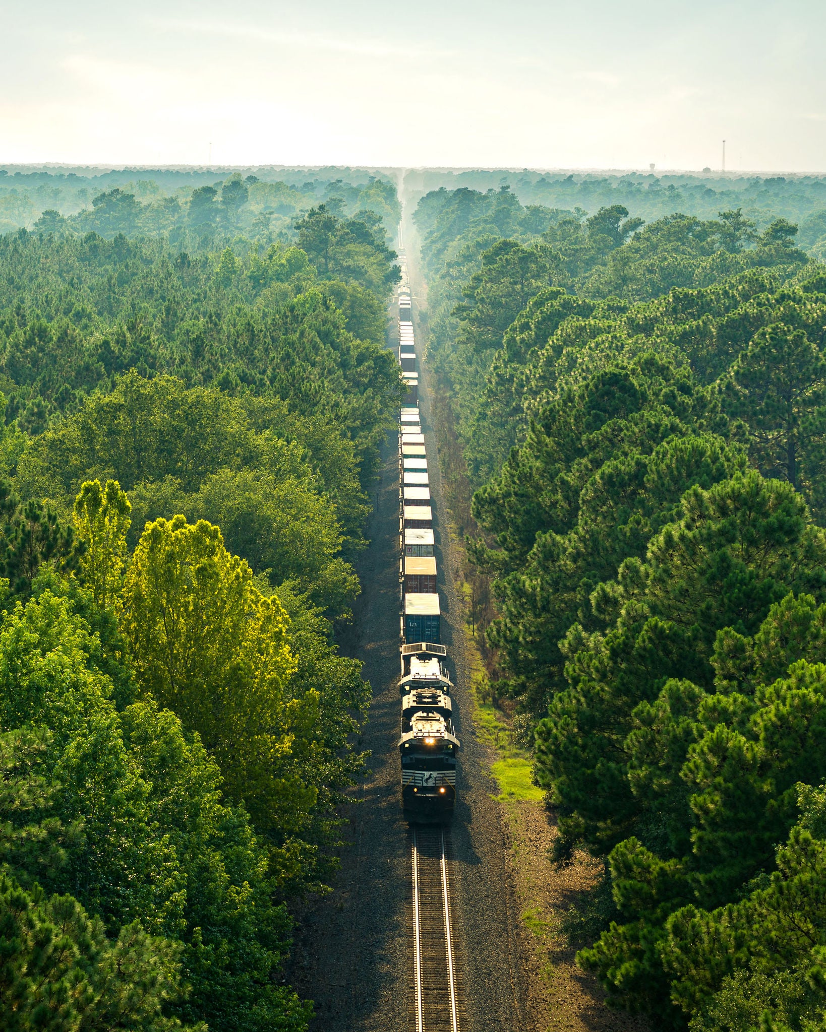 Aerial view of a train moving down a track surrounded by woods improving community safety