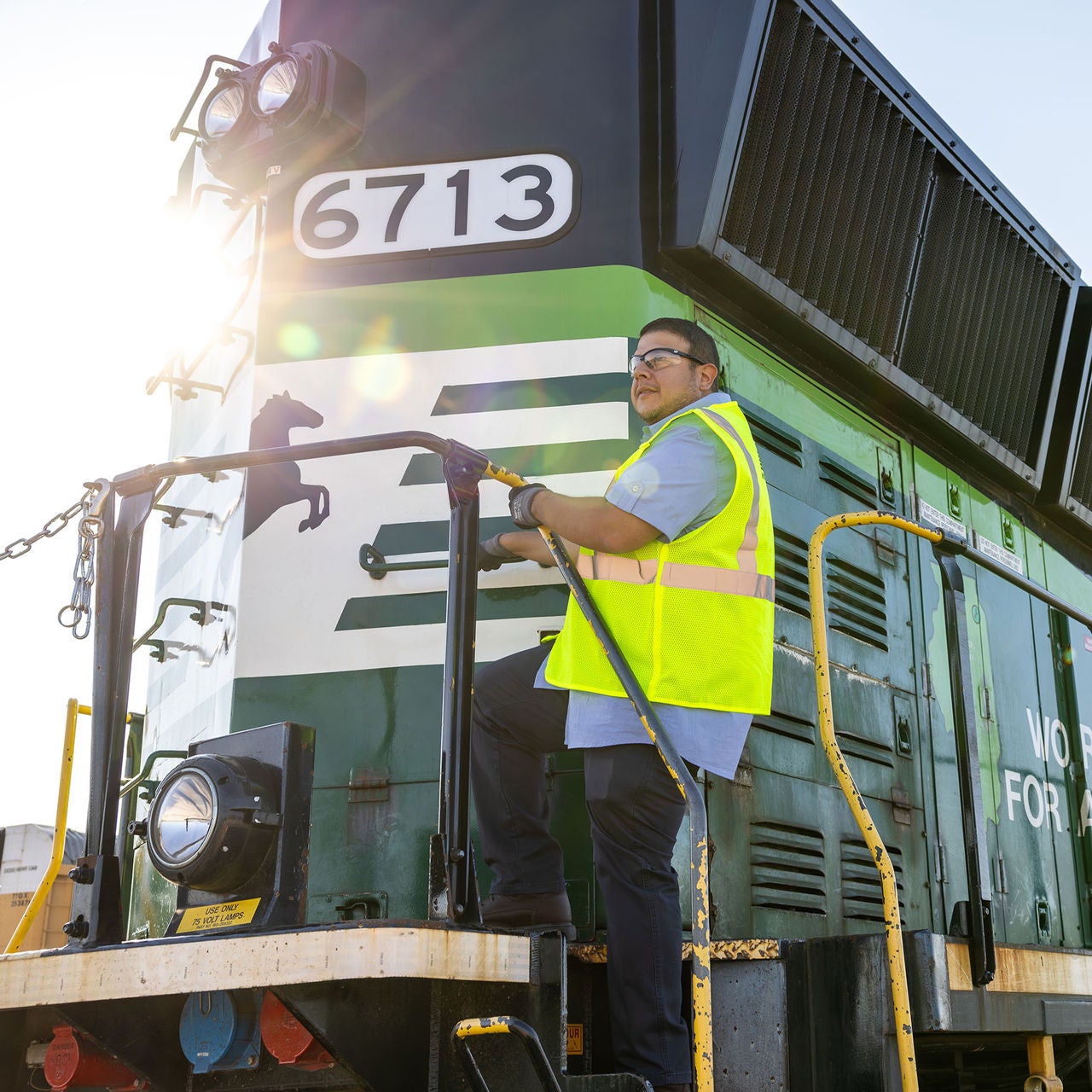 Person on the front of rail transportation company Norfolk Southerns eco train with a sun reflection on it