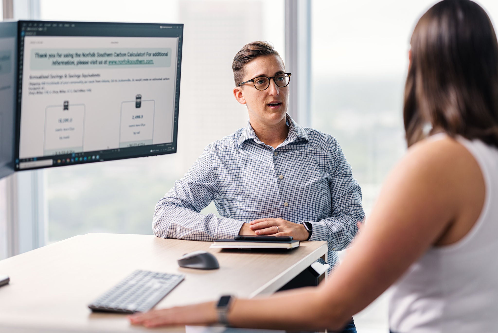 A man and women stand in front of a computer screen discussing the transportation industry